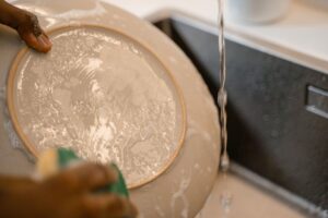 washing dishes in clean water. rinsing dinner plate.