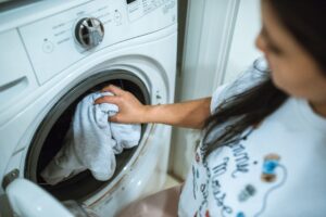 woman in t-shrt putting clothing in washing machine